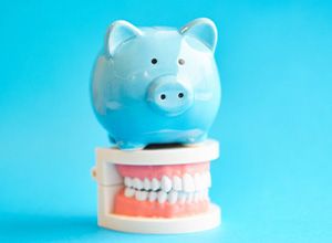 Blue piggy bank standing on a dental model