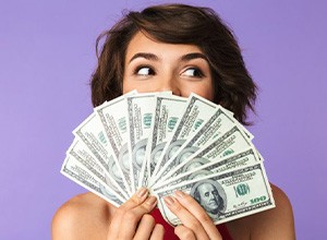 Woman fanning several dollar bills over her smile