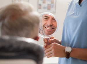 Patient smiling at reflection in handheld mirror