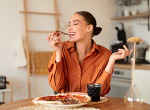 Woman enjoying slice of pizza at home