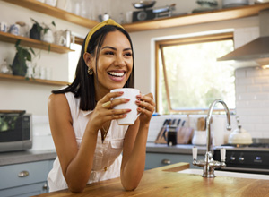 Woman smiling while drinking coffee in kitchen