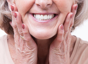 Woman smiling and pressing her hands to her face