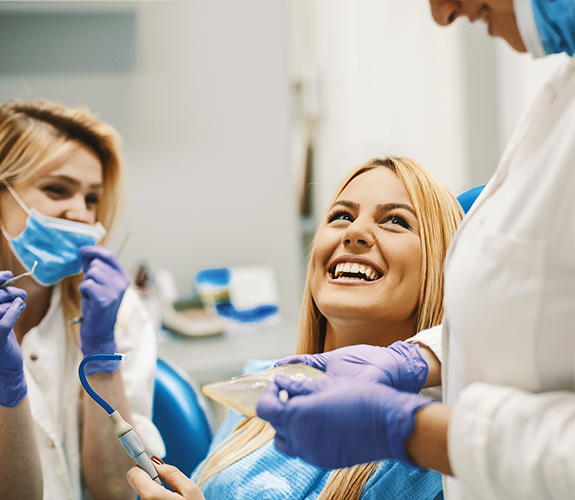 Blonde dental patient smiling up at dentist