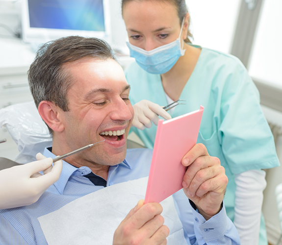 Senior dental patient checking smile in handheld mirror