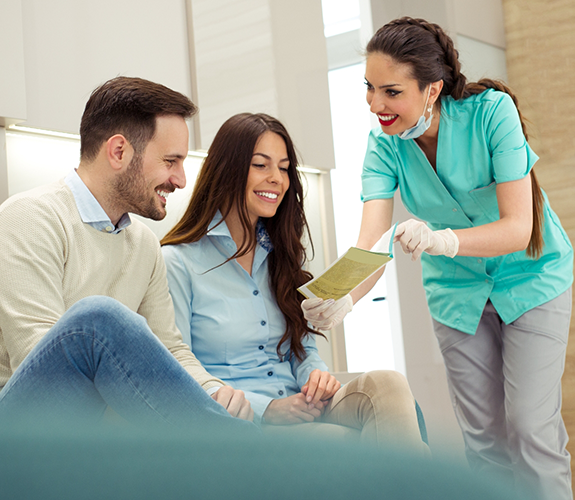 Dental team member showing man and woman a pamphlet