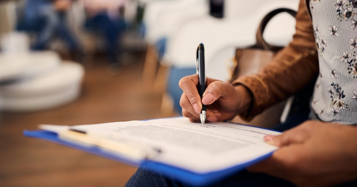 Filling out form on clipboard with pen