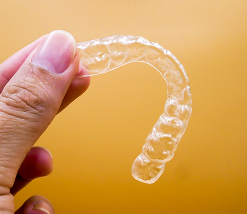 Close up of hand holding a clear aligner