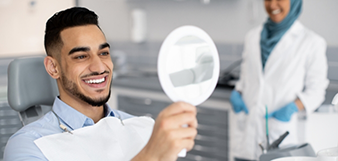 Male dental patient checking smile in mirror