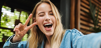 Woman smiling and holding up peace sign