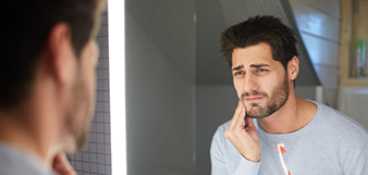 Man with tooth pain looking in mirror