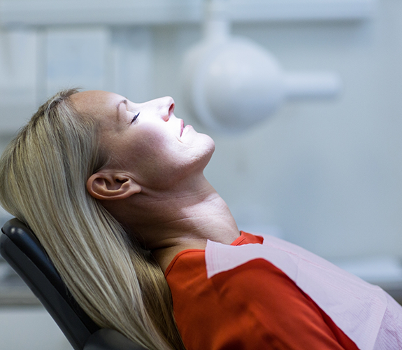 Relaxed woman in red shirt sitting back in dental chair