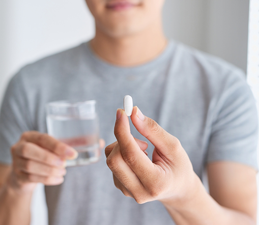 Man holding glass of water and a pill