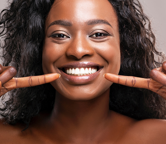 Woman smiling and pointing to her teeth