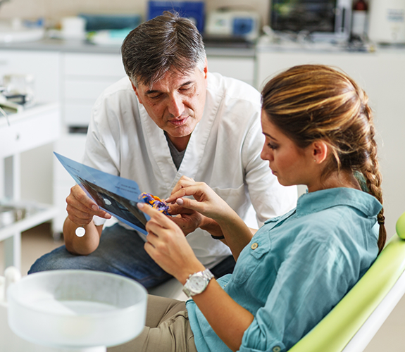 Dentist showing clipboard to female patient