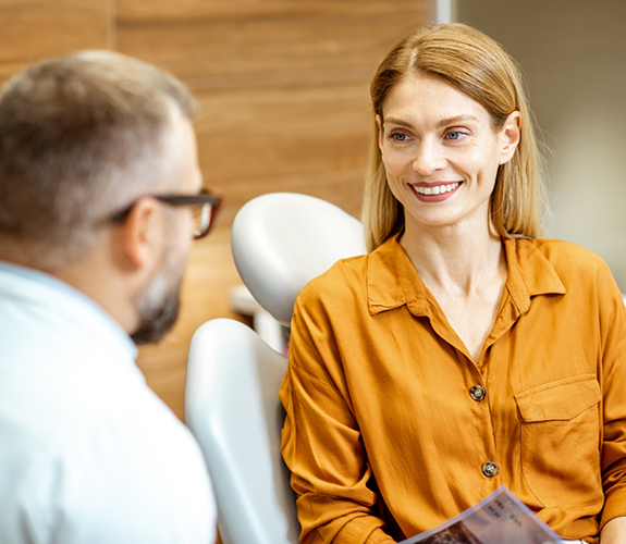 Woman in orange shirt speaking to dentist