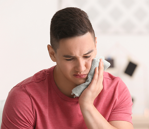 Young man applying ice to jaw