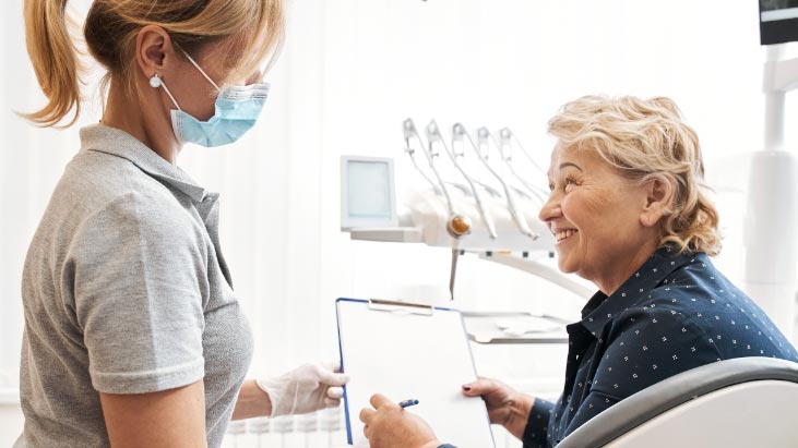 dentist helps mature woman filling out form