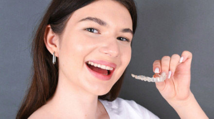 woman-smiling-holding-invisalign-clear-aligners